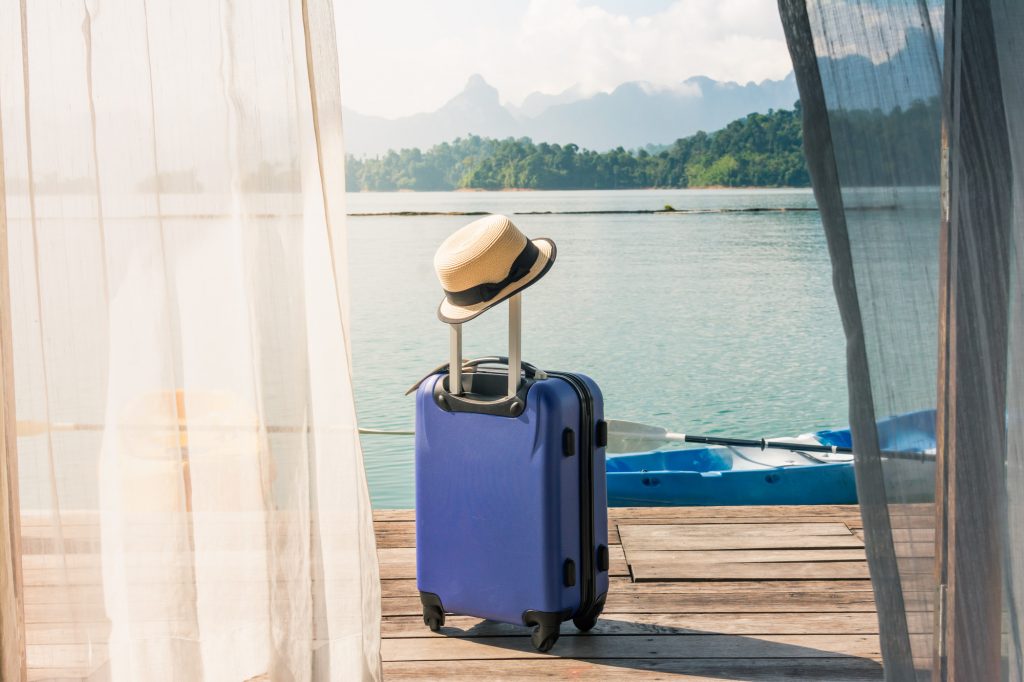 Valise sur une terrasse donnant sur un lac, un voyage bien planifié avec des conseils de voyage et Covid-19.