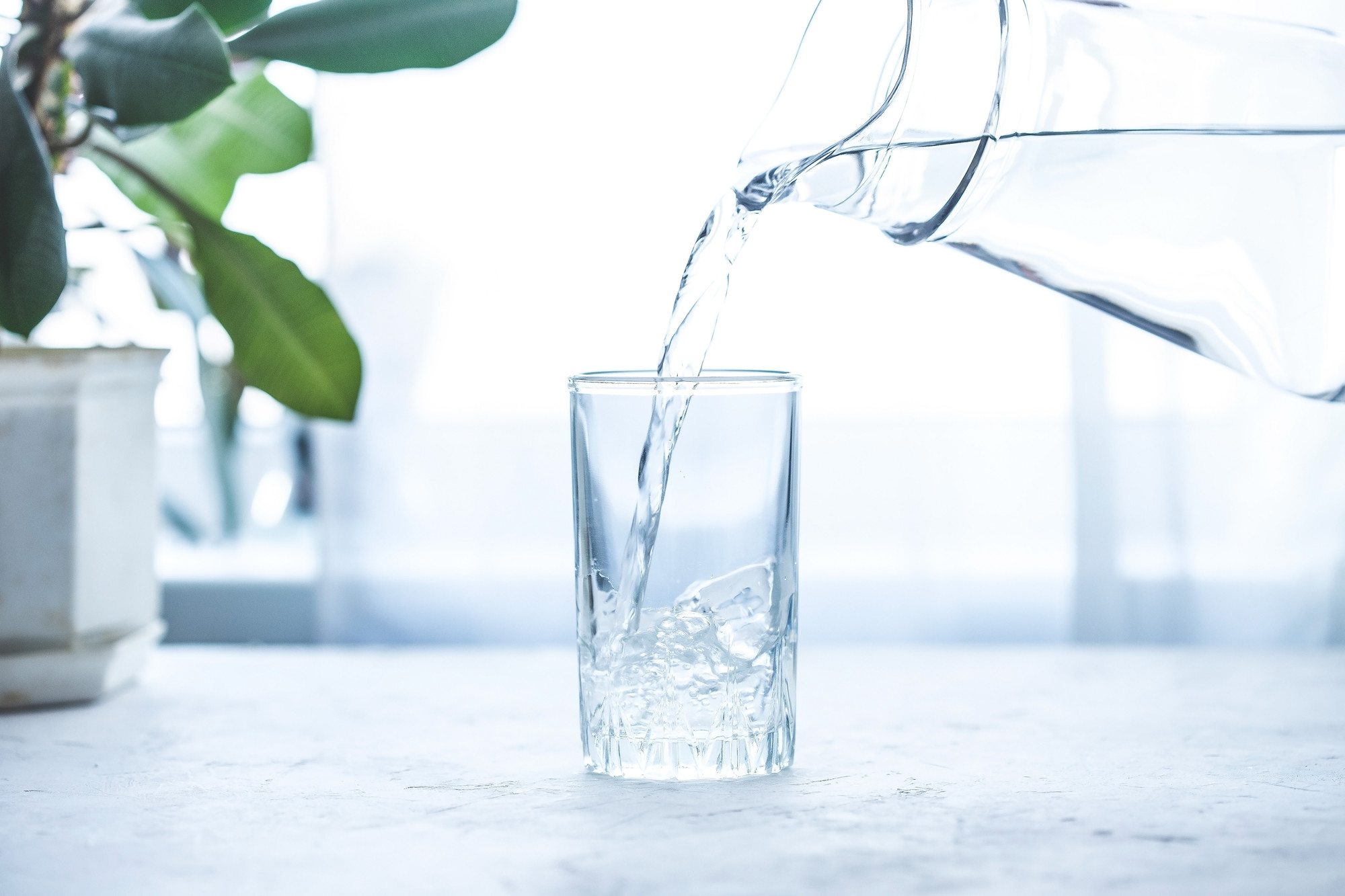 Versement d'eau dans un verre sur une table blanche 