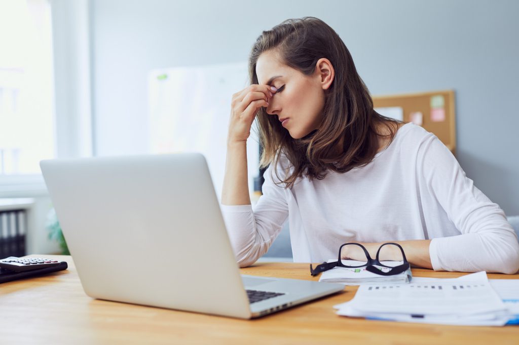 jeune employée de bureau stressée, assise à son bureau, se tenant la tête à cause du stress au bureau