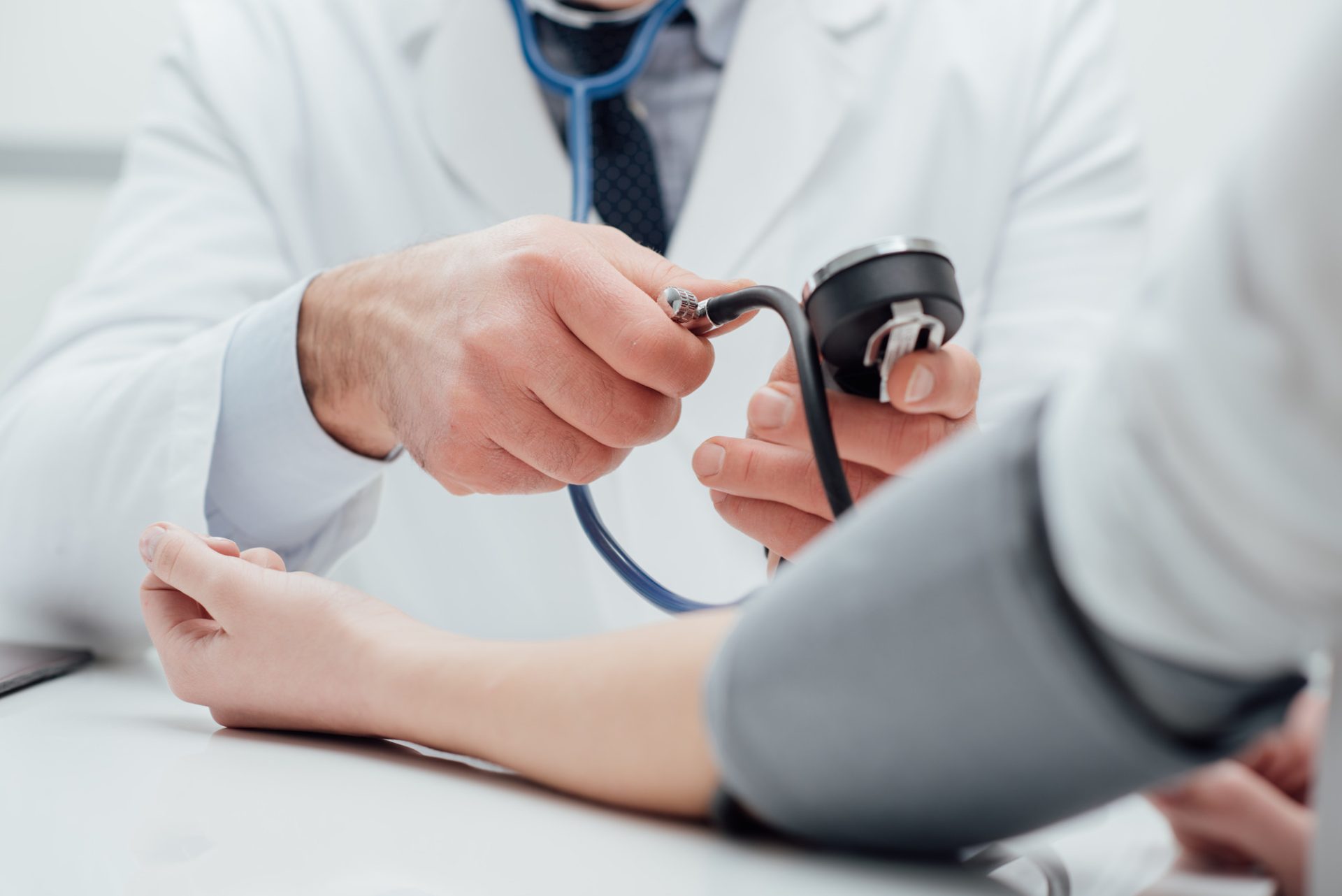 Hypertension selon l'Ayurveda - un médecin vérifie la tension artérielle d'un patient, il mesure le pouls avec un sphygmomanomètre, mains rapprochées.