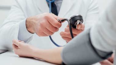 Hypertension selon l'Ayurveda - un médecin vérifie la tension artérielle d'un patient, il mesure le pouls avec un sphygmomanomètre, mains rapprochées.