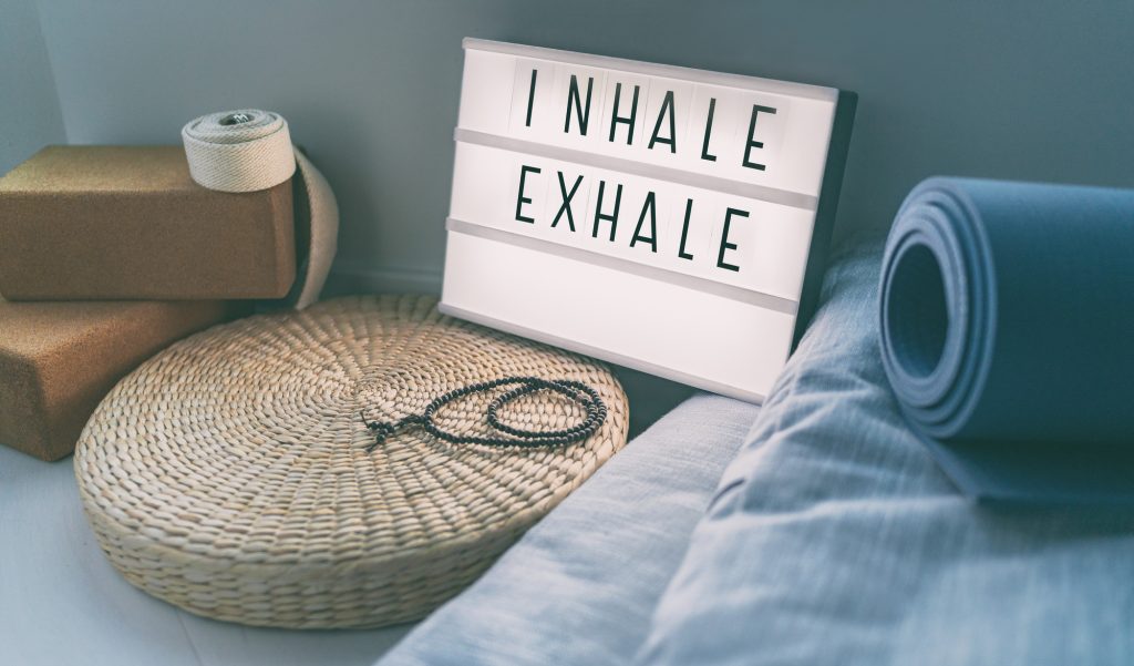Signe de respiration de yoga INHALE EXHALE lors d'un cours de fitness sur un message d'inspiration en lightbox avec tapis d'exercice, perles de mala, coussin de méditation. Accessoires pour un style de vie sain à la maison.
