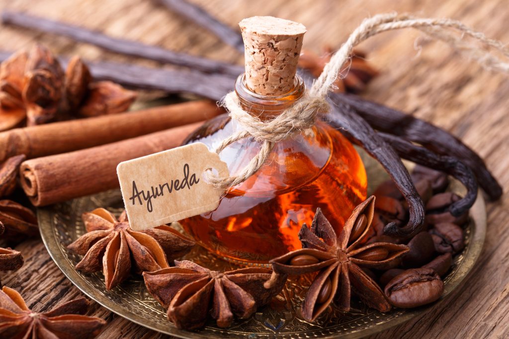 huile de massage ayurvédique pour la ménopause dans une fiole sur une table en bois
