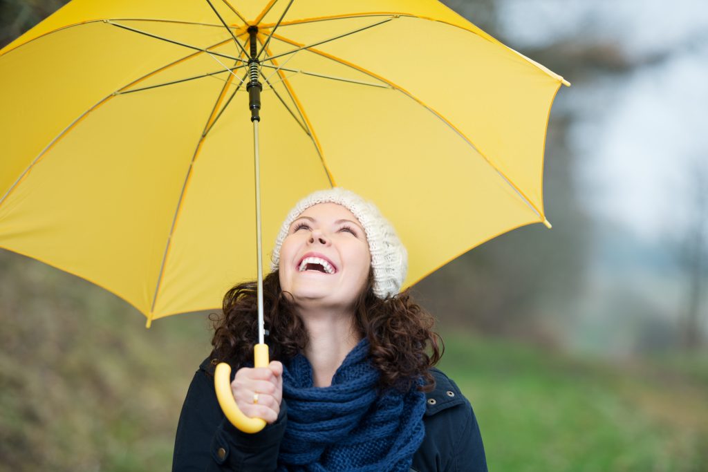 Mal de gorge et Ayurveda, une femme tient un parapluie jaune et souri vers le ciel