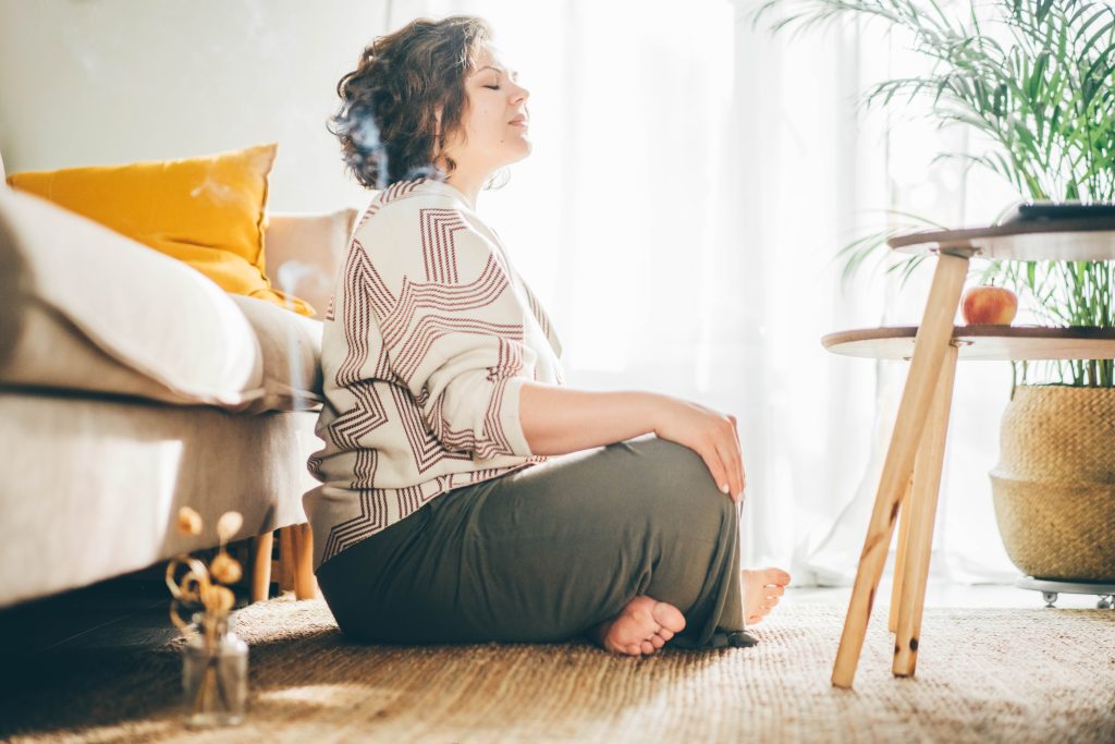 Ayurveda contre le rhume, une femme assise en tailleur et méditant dans son salon