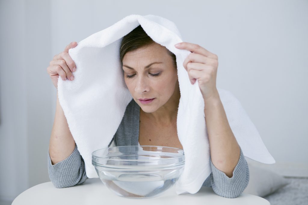 Mal de gorge et Ayurveda - une femme faisant un bain de vapeur avec une serviette et un bol d'eau chaude